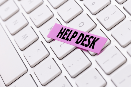 computer keyboard with pink tape that says "help desk"